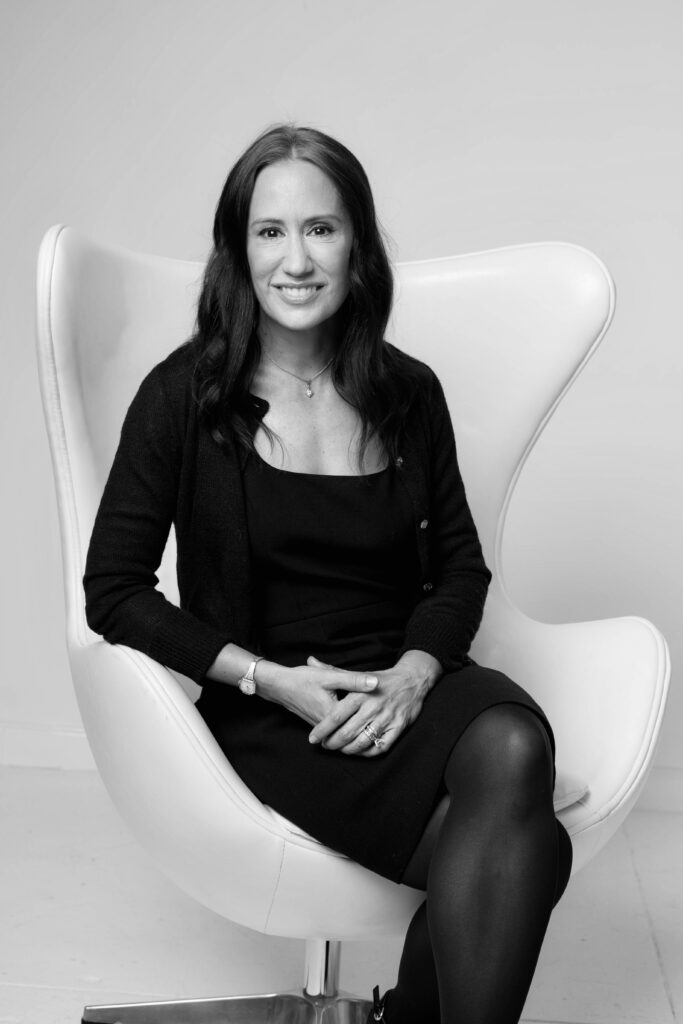 A woman sitting in an egg chair wearing black.