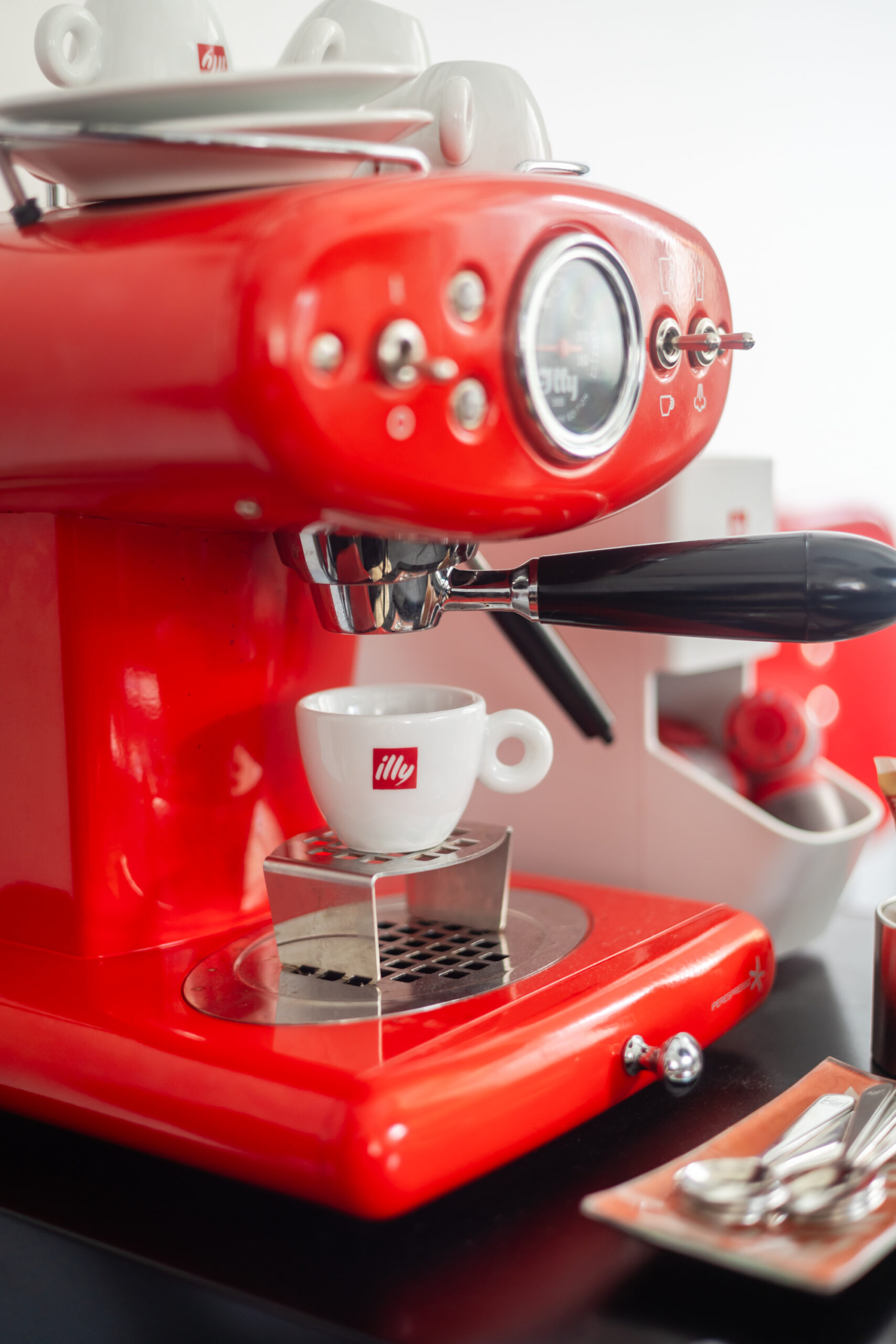 A red espresso machine with a cup of coffee on top.